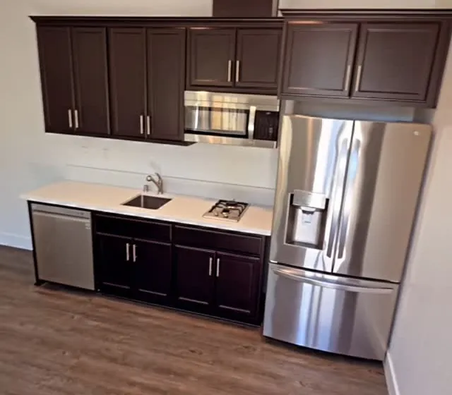 Studio kitchen with dark cabinets and stainless fridge
