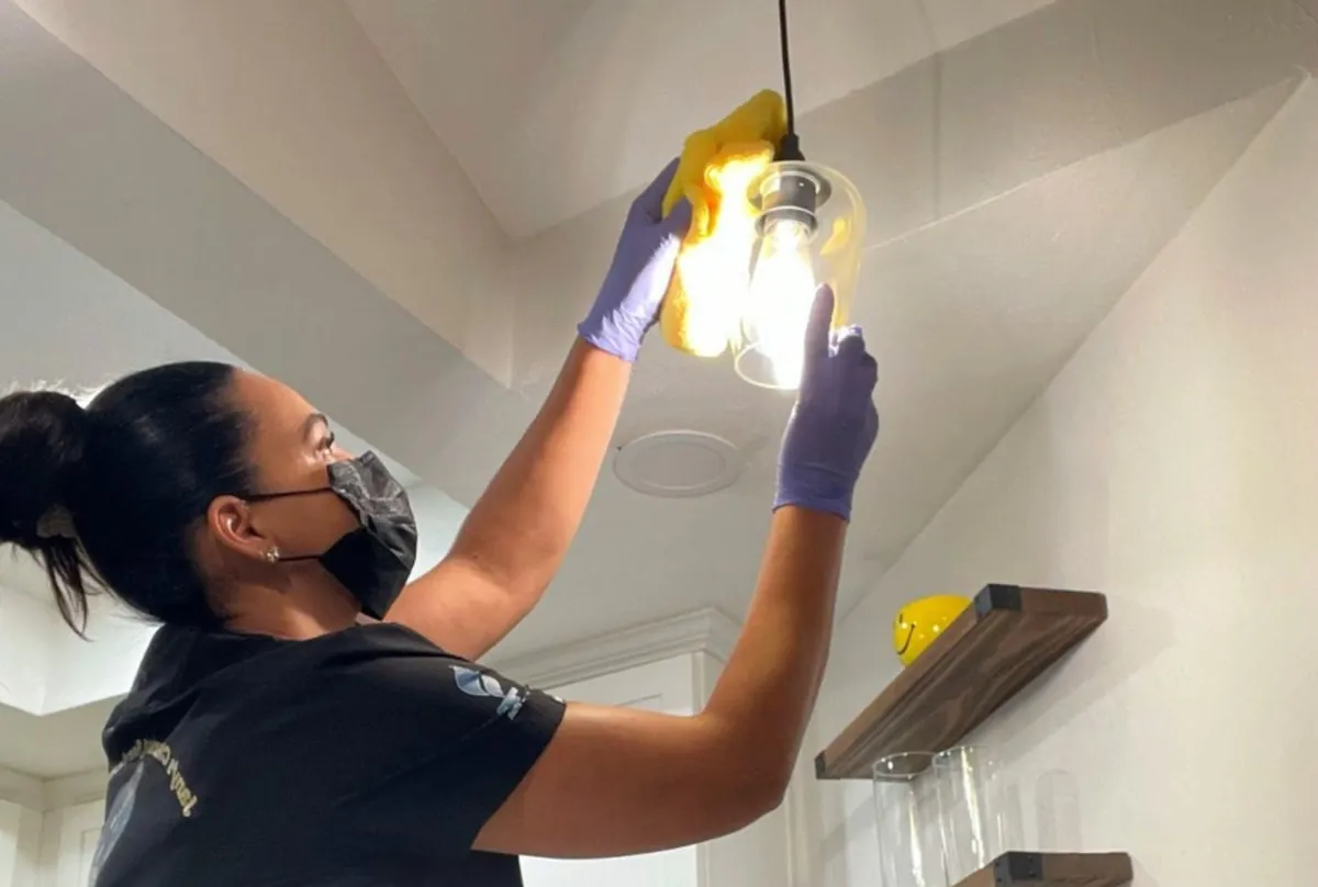 Team member cleaning a light fixture